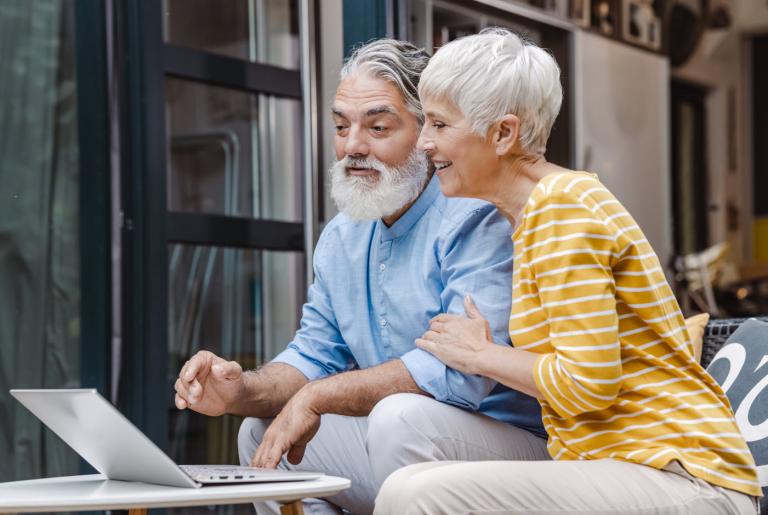 Un hombre y una mujer que sonríen ante una computadora portátil. 