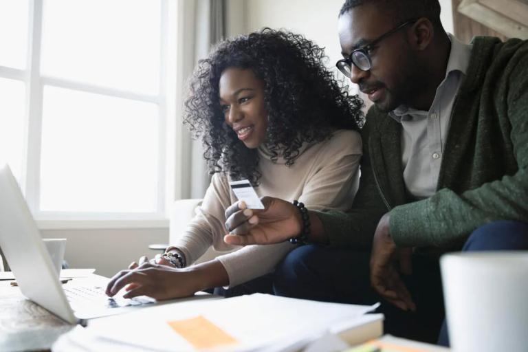 Man and Woman with laptop holding card